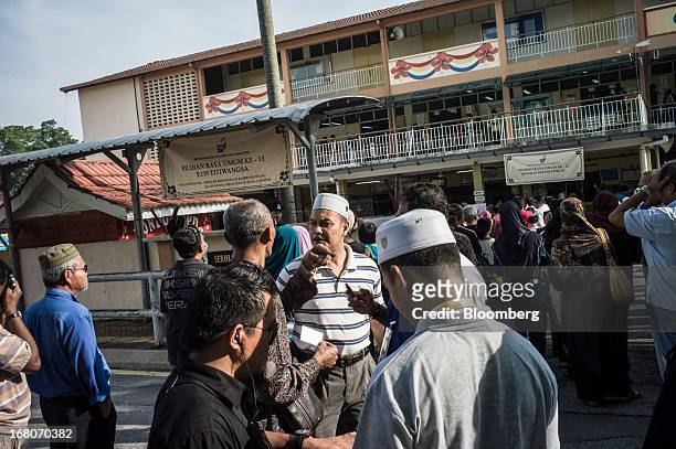 Voters wait in line outside a polling station for the general election in the Kampung Baru area of Kuala Lumpur, Malaysia, on Sunday, May 5, 2013....