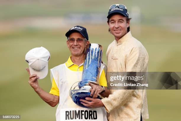 Brett Rumford of Australia holding the winner's trophy poses with his caddie after winning the final round of the Volvo China Open at Binhai Lake...