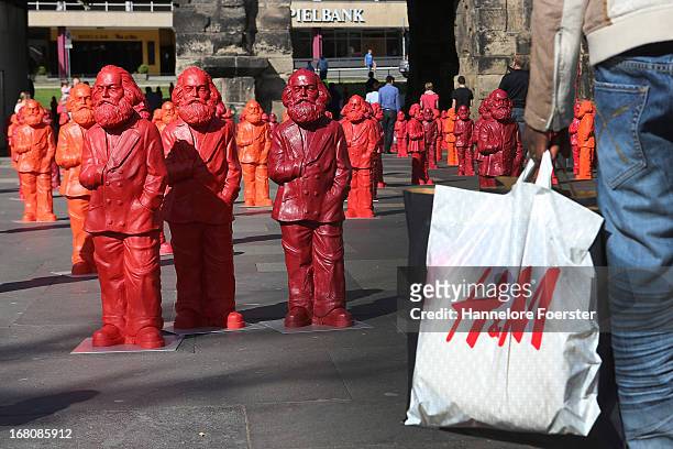 Visitors with a H&M bag walk among some of the 500, one meter tall statues of German political thinker Karl Marx on display on May 5, 2013 in Trier,...