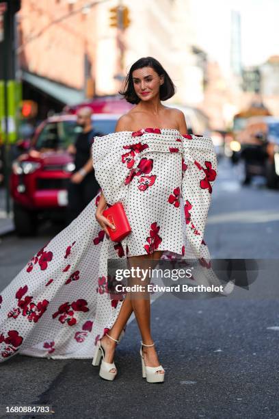 Guest wears a bridal face veil, a red and white off-shoulder floral print pattern midi on-knee and long dress with printed polka dots, white platform...