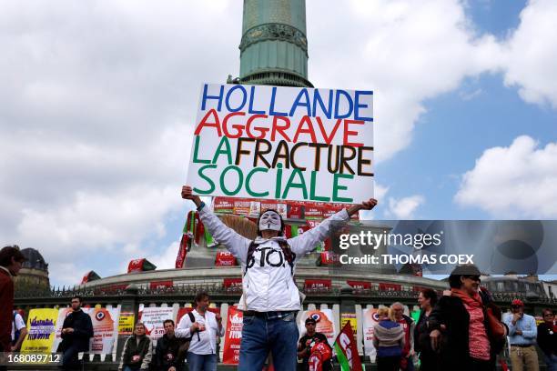 Protester wearing an anonymous Guy Fawkes mask holds a placard reading "Hollande aggravates social divisions" as he takes part in a demonstration on...