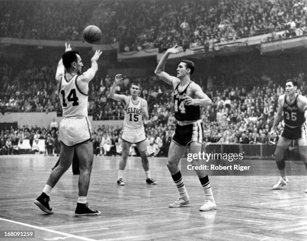 Bob Cousy of the Boston Celtics passes to teammate Tom Heinsohn as Jerry West of the Los Angeles Lakers defends during an NBA game circa 1962 at the...