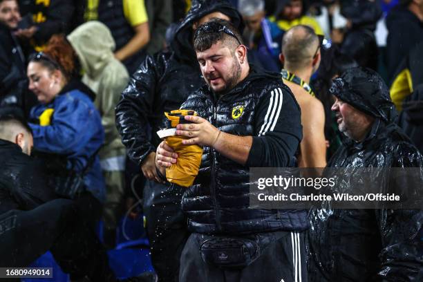 An AEK Athens fan squeezes rainwater out of his flag during the UEFA EUROPA League match between Brighton & Hove Albion and AEK Athens at American...