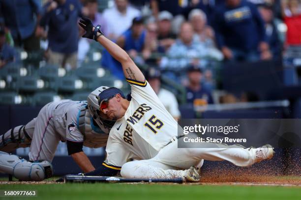 Tyrone Taylor of the Milwaukee Brewers beats a tag at home by Jacob Stallings of the Miami Marlins during the fifth inning at American Family Field...