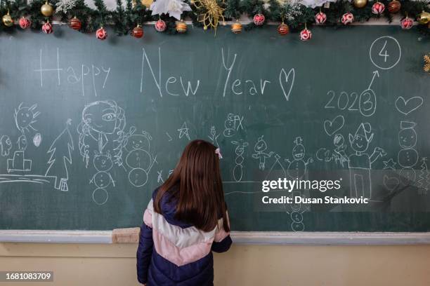 menina da escola primária que decora uma sala de aula para o ano novo - século xxi - fotografias e filmes do acervo