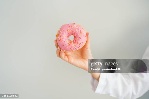 female healthy nutritionist holding donut with her hand - fat people eating donuts stock pictures, royalty-free photos & images