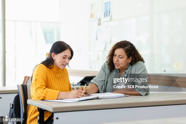 female college student watches female tutor work math problem - one on one stock pictures, royalty-free photos & images