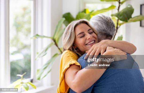 donna amorevole che abbraccia suo marito a casa - home sweet home espressione inglese foto e immagini stock