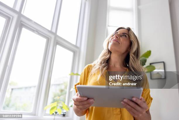 woman controlling her smart home on a digital tablet - dimmer switch stock pictures, royalty-free photos & images
