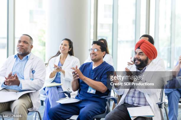 appreciative diverse medical professionals applaud unseen speaker - american college of physicians stock pictures, royalty-free photos & images