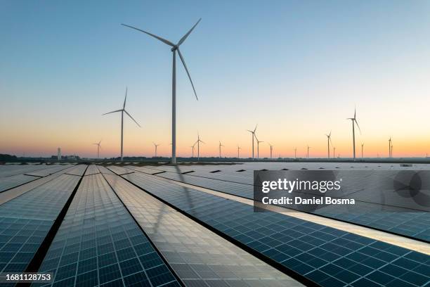 solar energy field and wind turbines during a summer sunrise - producción de combustible y energía fotografías e imágenes de stock