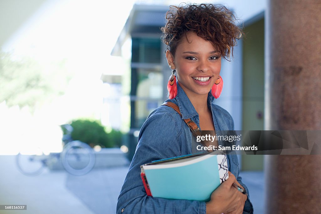 Smiling student carrying folder outdoors