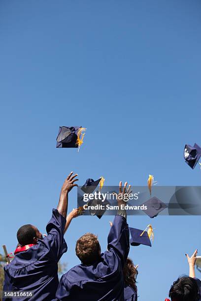 absolventen werfen kappen in der luft im freien - graduation hat stock-fotos und bilder