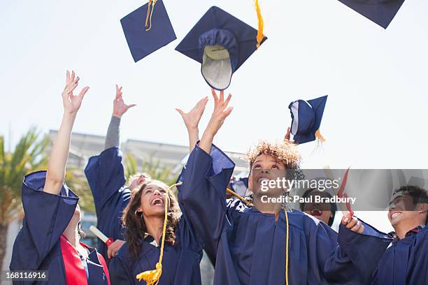 absolventen herumwerfen kappen in der luft - graduation hat stock-fotos und bilder
