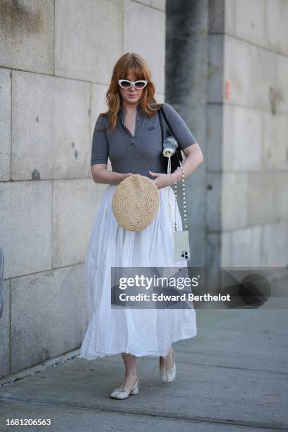 Guest wears sunglasses, a gray polo shirt, a white gathered pleated midi skirt, white shoes, outside Gabriela Hearst, during New York Fashion Week,...