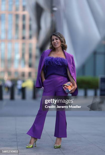 Olga Ferrara is seen wearing silver earrings with green diamonds; a matching outfit from Milly in purple, consisting of a blazer with shoulder pads...