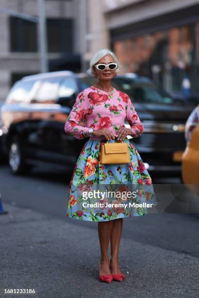 Grece Ghanem is seen wearing sunglasses with white frame from Bottega Veneta, red hoop earrings with pearls, a pink cropped cardigan with red/green...