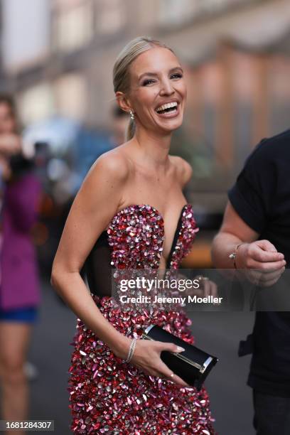 Leonie Hanne is seen wearing diamond earrings; a sleeveless midi dress with countless crystals and sequins in red and pink, a deep neckline and a...