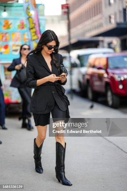 Guest wears sunglasses, a black blazer jacket, black shorts, cowboy boots, outside Carolina Herrera, during New York Fashion Week, on September 12,...