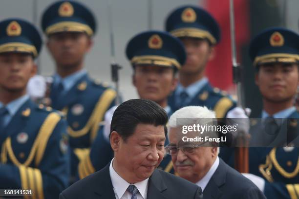Chinese President Xi Jinping accompanies Palestinian President Mahmoud Abbas to view an honour guard during a welcoming ceremony outside the Great...