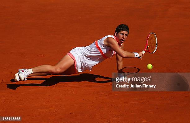 Carla Suarez Navarro of Spain stetches for a shot as she falls to the clay in her match against Sam Stosur of Australia during day three of the Mutua...