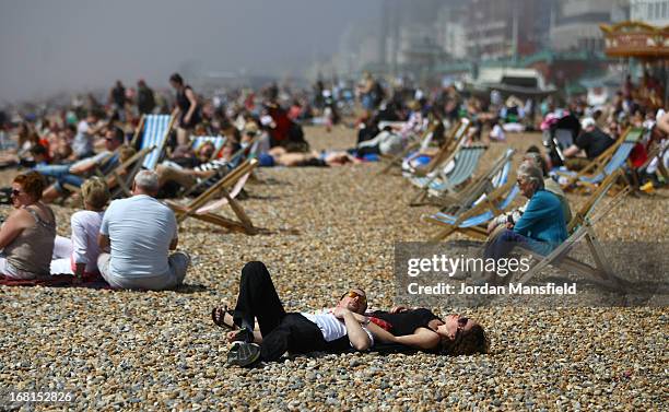 Visitors relax on Brighton Beach on May 6, 2013 in Brighton, England. Visitors have flocked to Brighton Beach as the Met Office predict the May Day...