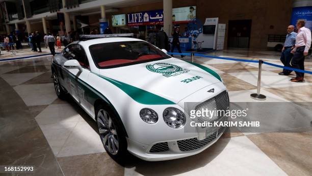People walk past the new Dubai police Bentley patrol car on display during the Arabian Travel Market at the Dubai World Trade Centre in the Emirati...