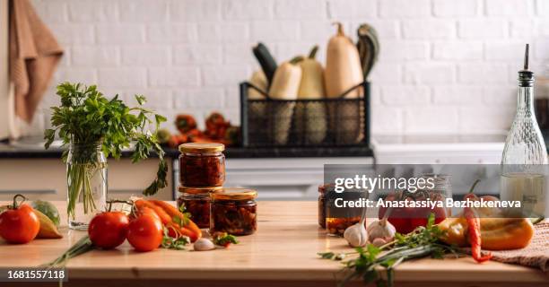 glass jars with sun-dried tomatoes on a wooden table with vegetables in front of the kitchen - kazakhstan food stock pictures, royalty-free photos & images