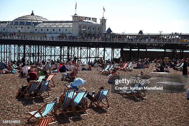 People relax on the beach in front of Brighton Pier on May 6, 2013 in Brighton, England. Visitors have flocked to Brighton Beach as the Met Office...