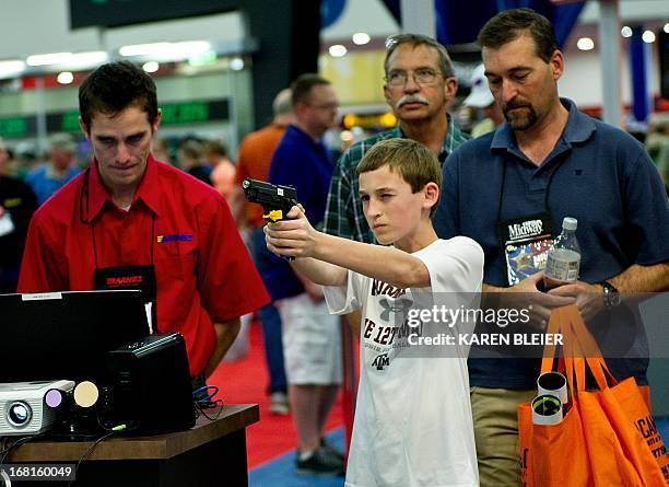 Younster tests his shooting skills with a handgun using a computer simulator during the 142nd annual National Rifle Association convention at the...