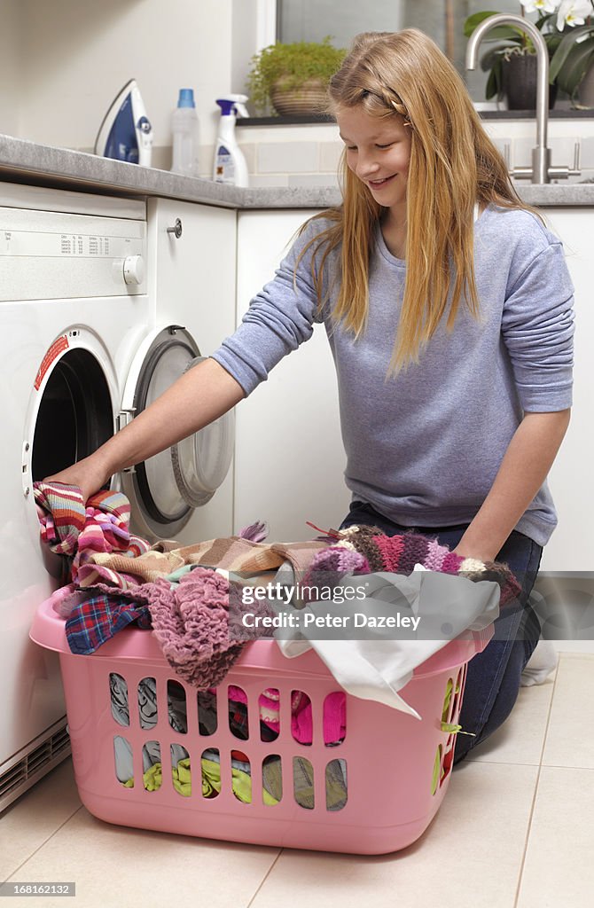 Young girl loading washing machine