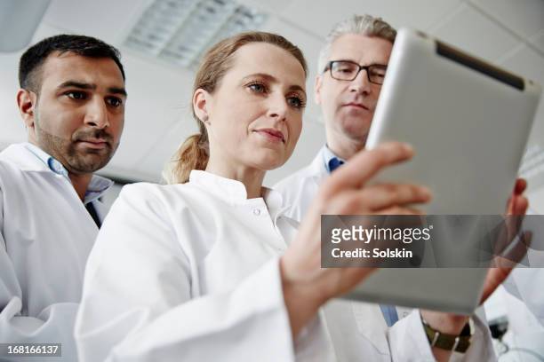 three scientists in a laboratory, using tablet - mobilität zukunft stock-fotos und bilder