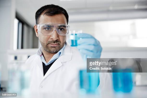 scientist examining samples in glass beakers - glass beaker stock pictures, royalty-free photos & images