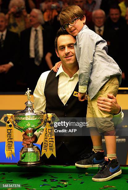 Ronnie O'Sullivan of England poses with the trophy and his son Ronnie after winning against Barry Hawkins of England in the final match of the World...
