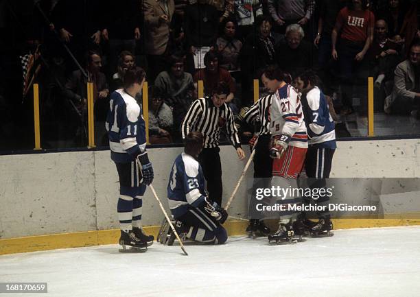 Ted Irvine of the New York Rangers looks down at Eddie Shack of the Pittsburgh Penguins as Shack's teammates Nick Harbaruk and Bryan Hextall talk to...