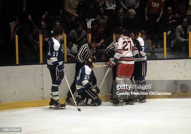 Ted Irvine of the New York Rangers looks down at Eddie Shack of the Pittsburgh Penguins as Shack's teammates Nick Harbaruk and Bryan Hextall talk to...