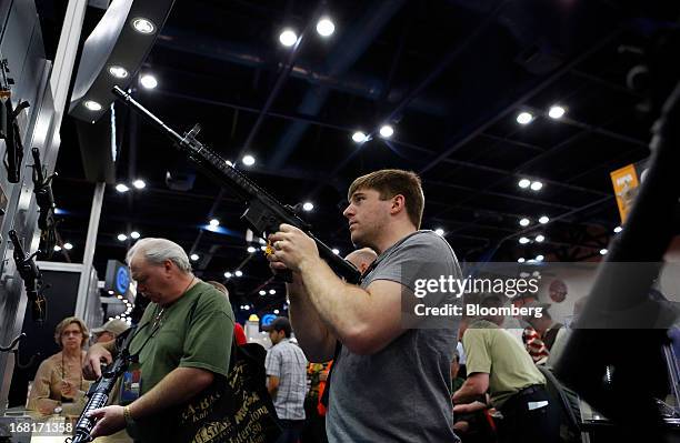 Attendees look at Colt Defense LLC rifles during the 2013 National Rifle Association Annual Meetings & Exhibits at the George R. Brown Convention...