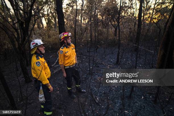 This picture taken on September 15, 2023 shows New South Wales Rural Fire Service volunteers Mark Davis and Andy Hain inspecting bushland after a...