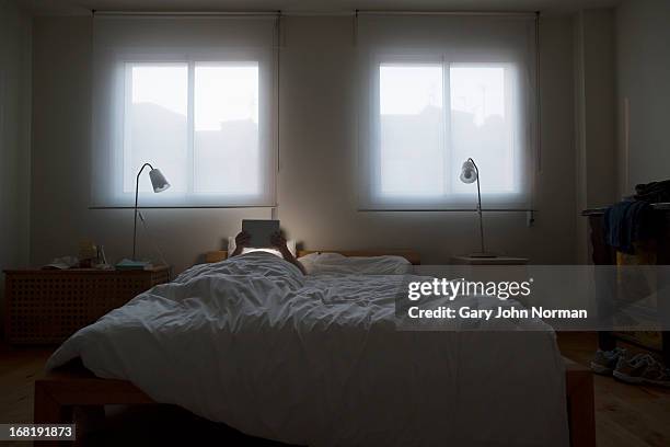 using tablet at night in bed - norman window fotografías e imágenes de stock