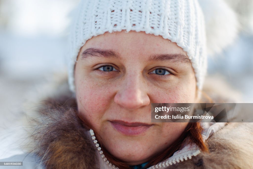 A close-up portrait of an adult woman's face in the cold in winter