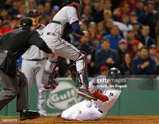 Stephen Drew of the Boston Red Sox is out at the plate as Joe Mauer of the Minnesota Twins leaps for a throw and tags out Drew in the 5th inning at...
