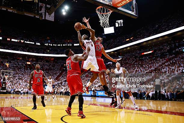 LeBron James of the Miami Heat shoots is guarded by Joakim Noah and Jimmy Butler of the Chicago Bulls during Game One of the Eastern Conference...