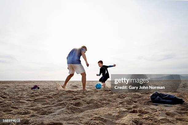 dad and sons playing football on the beach - beach family stock-fotos und bilder