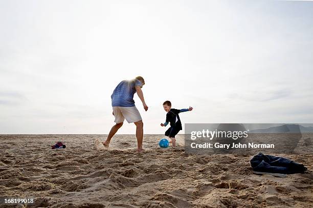 dad and sons playing football on the beach - leren korte broek stockfoto's en -beelden