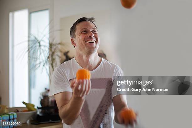 man juggling with oranges, smiling - juggling stock pictures, royalty-free photos & images