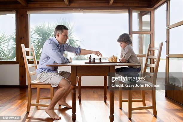 dad and young son playing chess - boyshorts fotografías e imágenes de stock