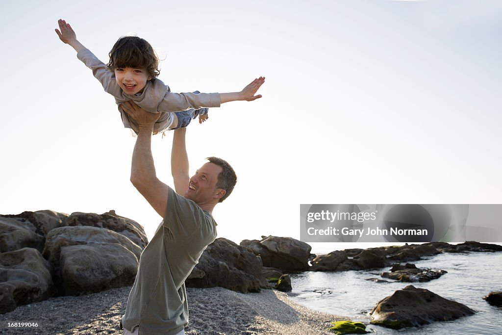 Dad lifts young son above his head on beach