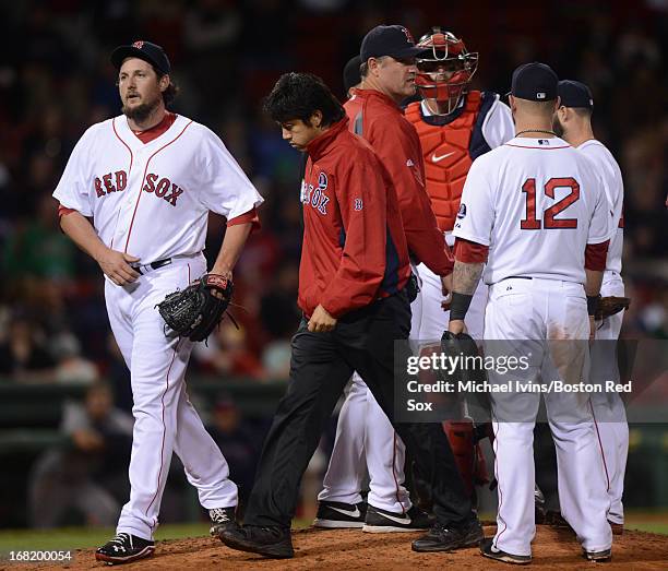 Joel Hanrahan of the Boston Red Sox walks off the field with trainer Masai Takahashi after giving up a lead against the Minnesota Twins in the ninth...