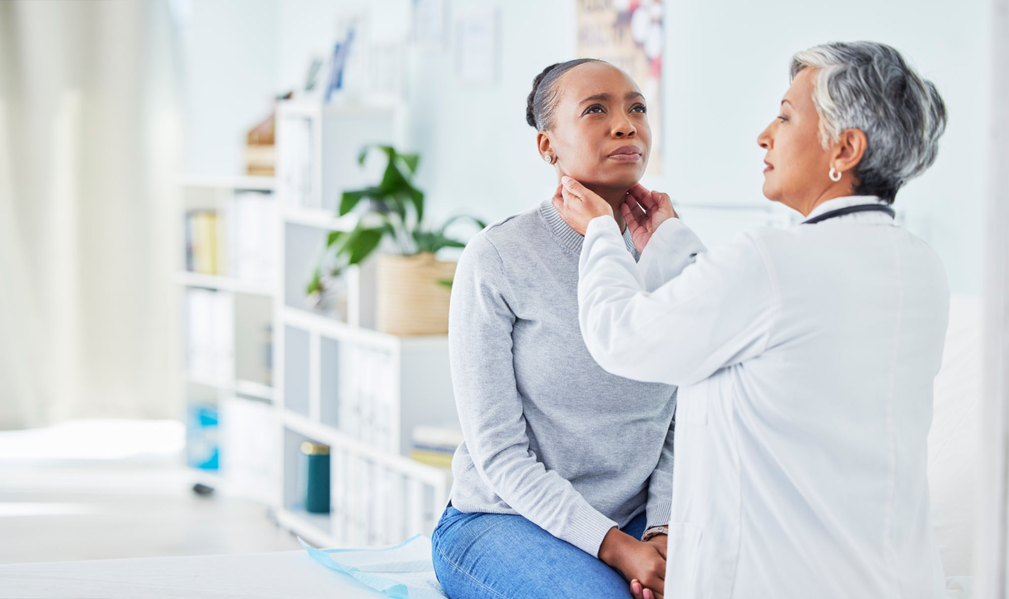 Doctor, patient and feel throat in hospital of a black woman with virus, pain or infection. Health care worker and sick person check glands or sore neck for thyroid, tonsils or medical lymph nodes Doctor, patient and feel throat in hospital of a black woman with virus, pain or infection. Health care worker and sick person check glands or sore neck for thyroid, tonsils or medical lymph nodes