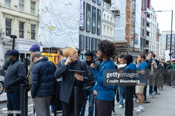 Employees from the Apple Inc. Regent Street store talk with customers queuing outside ahead of opening on the first day of sale of the iPhone 15...